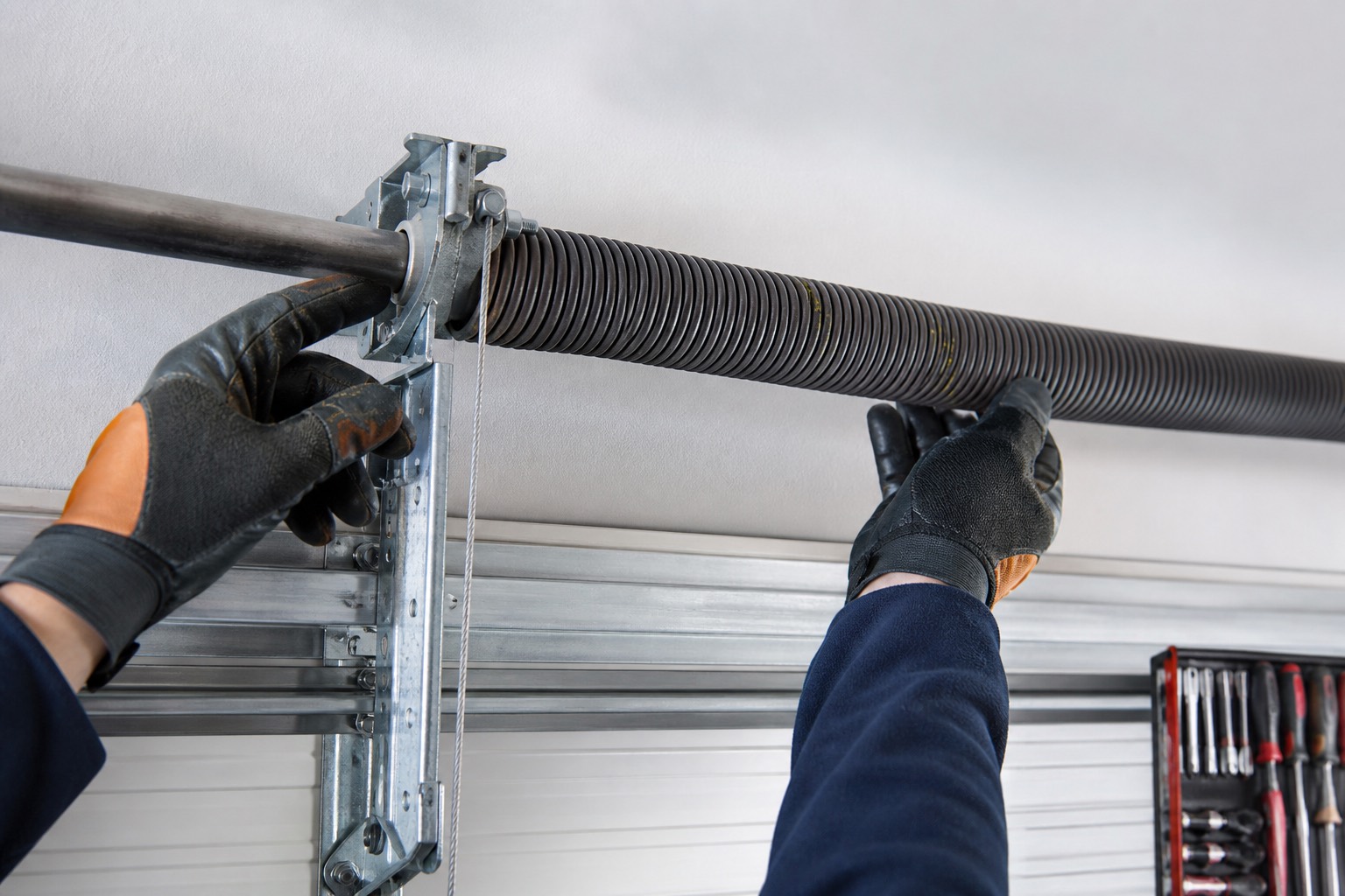 Technician inspecting a garage door torsion spring